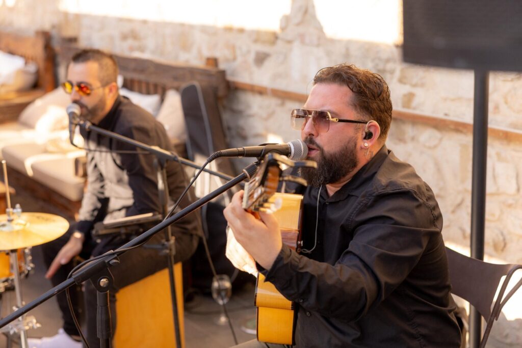 Guitarrista cantando ante un micrófono junto a un percusionista.