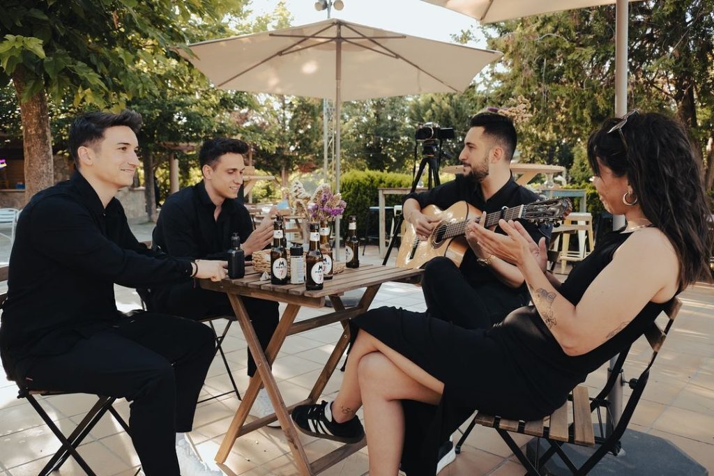 Musiker sitzen mit einer Gitarre zusammen an einem Tisch.