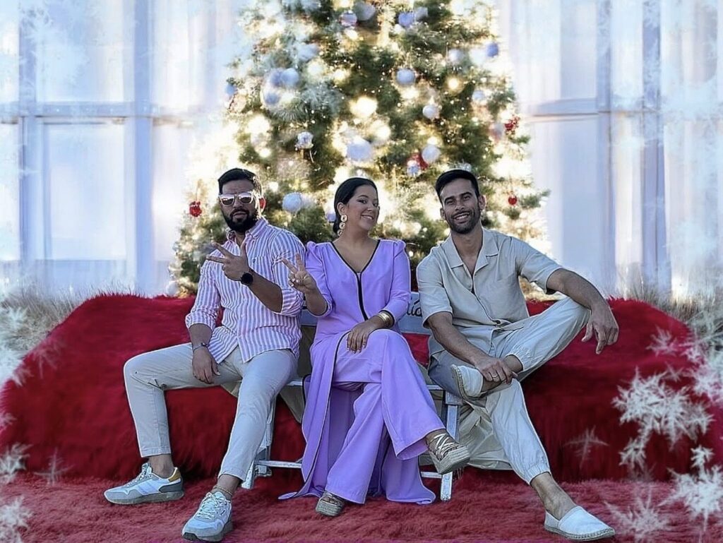 Tres músicos sentados ante un árbol y decoración navideña.