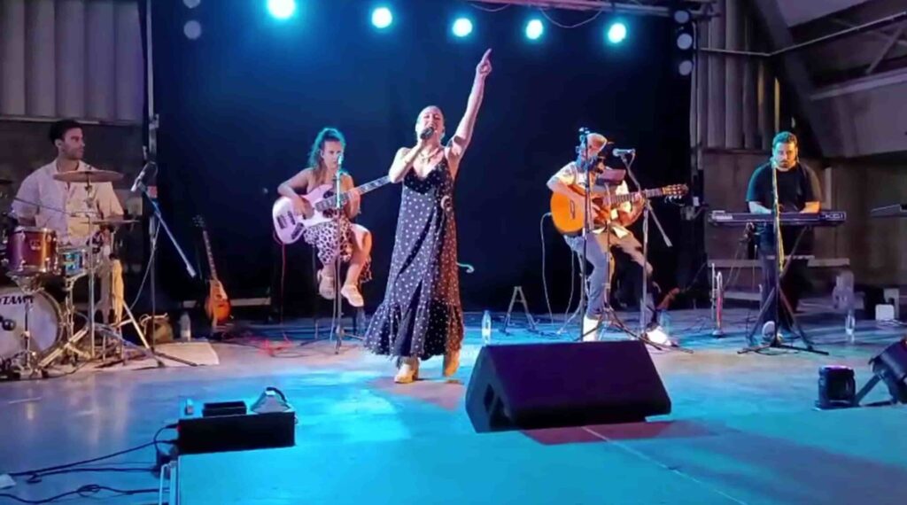Formación con cantante, bajo, guitarra, teclado y batería sobre un escenario.